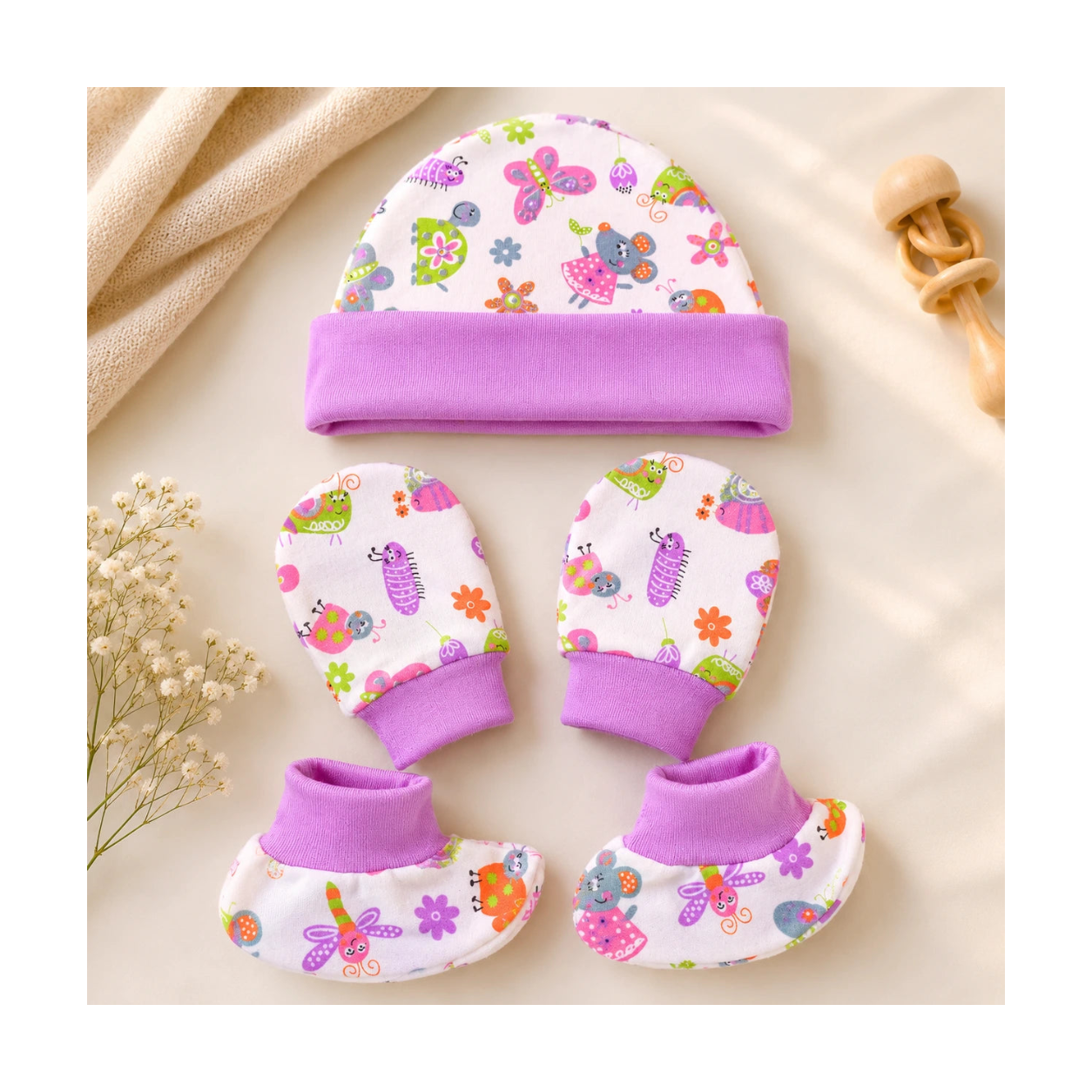 Baby hat, mittens, and booties set with colorful patterns on a beige background